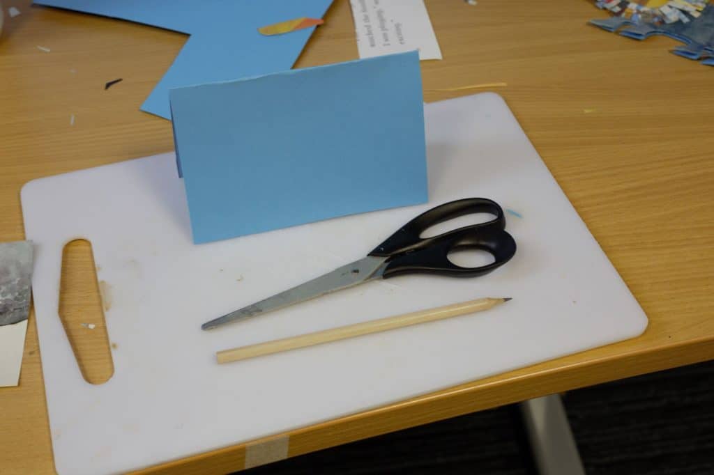 Crafting mat with card scissors and a pencil on top